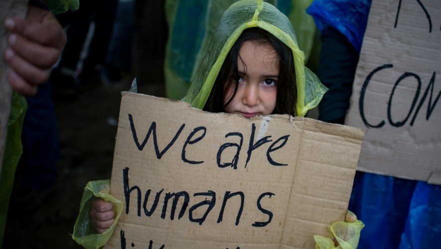 Une petite fille tient une pancarte pendant une manifestation de migrants pour la réouverture de la frontière gréco-macédonienne