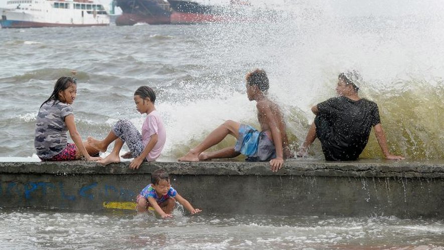 Des habitants de Manille s'amusent dans les vagues crées par l'arrivée du typhon Noul, le 10 mai 2015
