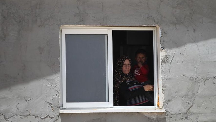 Une femme palestinienne tenant un enfant dans ses bras regarde de la fenêtre de sa maison dans le village de Deirat (sud de la Cisjordanie), le 21 avril 2015