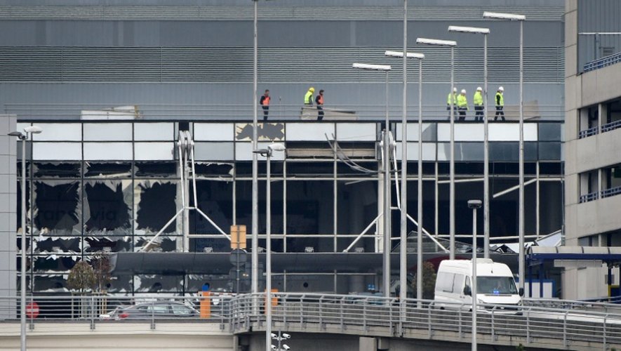 Des ouvriers marchent sur le toit de l'aéroport de Bruxelles à Zaventem le 23 mars 2016 au lendemain des attentats terroristes dans la capitale belge