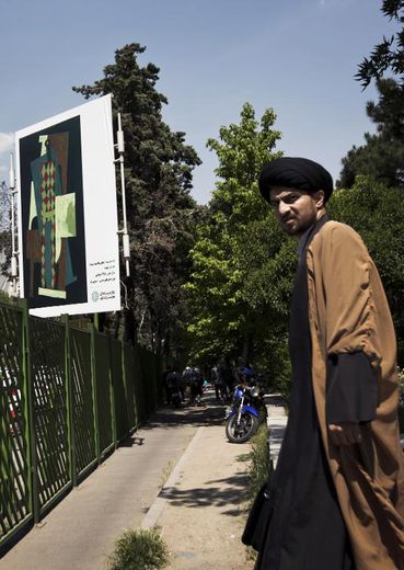 Un religieux iranien près d'une affiche de l'"Arlequin" de l'artiste espagnol Pablo Picasso à Téhéran, le 9 mai 2015