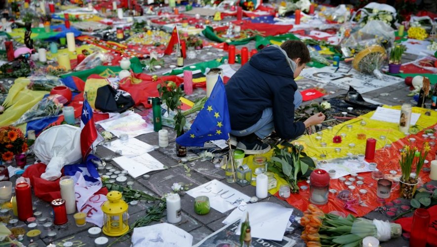 Un garçon allume une bougie en hommage aux victimes des attentats de Bruxelles, Place de la Bourse, le 23 mars 2016