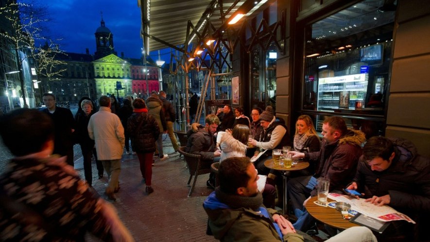 Des gens boivent un verre en terrasse près du Palais royal aux couleurs de la Belgique, à Amsterdam le 22 mars 2016
