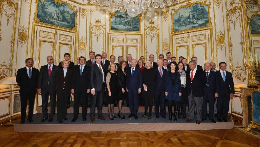 Jean-Marc Ayrault (c) pose aux côtés de membres de son gouvernement et de patrons d'entreprises internationales, le 16 février 2014 à Paris