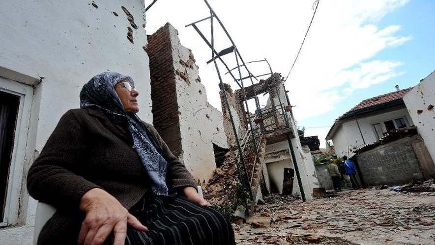 Une femme est assise à l'extérieur de sa maison en ruine, le 11 mai 2015 à Kumanovo, dans le nord de la Macédoine