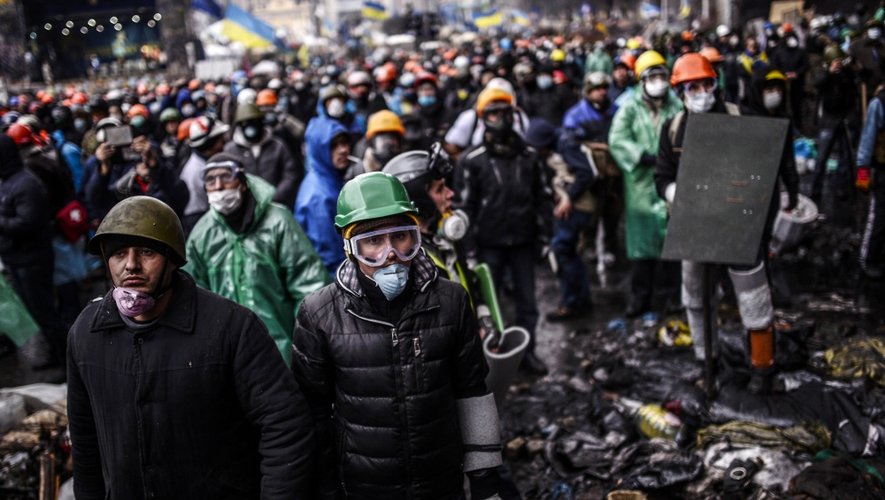 Des protestants postés derrière les barricades font face à la police à Kiev.