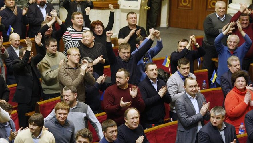 Des députés ukraniens applaudissent après le vote au Parlement d'une résolution "condamnant la violence qui a conduit à la mort de citoyens ukrainiens innocents", le 20 février 2014 à Kiev