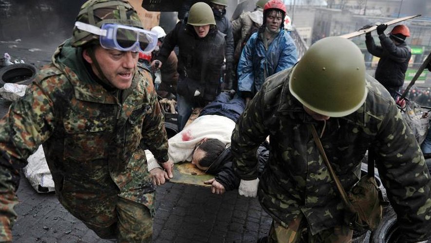 Des manifestants transportent le corps d'un blessé lors d'affrontements avec la police, le 20 février 2014 à Kiev