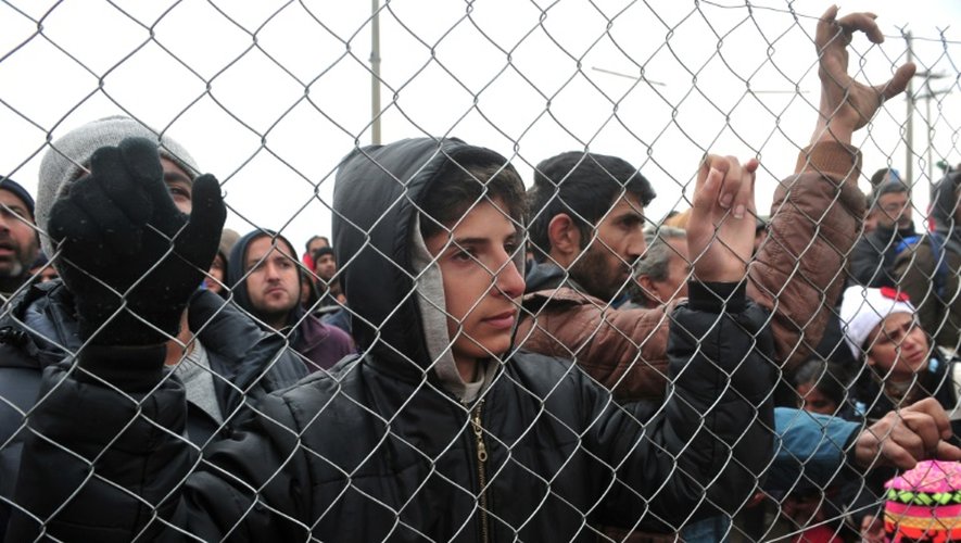 Des migrants derrière un grillage protestent à la frontière gréco-macédonienne près du village d'Idomeni le 27 mars 2016