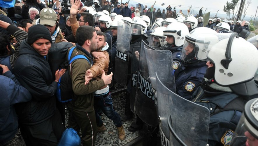 Des migrants protestent devant la police anti-émeute à la frontière gréco-macédonienne près du village d'Idomeni, le 27 mars 2016