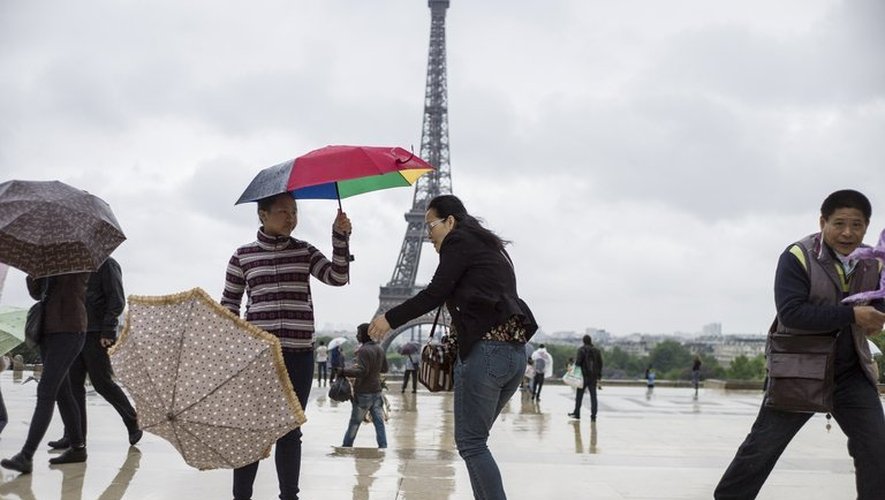 Des touristes avec leur parapluie devant la Tour Eiffel à Paris, le 20 mai 2013