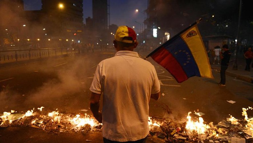 Un manifestant tient le drapeau vénézuélien lors d'un rassemblement contre le gouvernement de Nicolas Maduro, le 21 février 2014 à Caracas