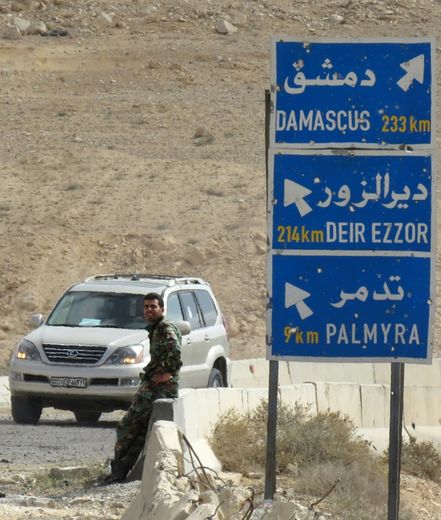 Un membre des forces gouvernementales syriennes près d'un panneau routier, le 27 mars 2016 à Palmyre