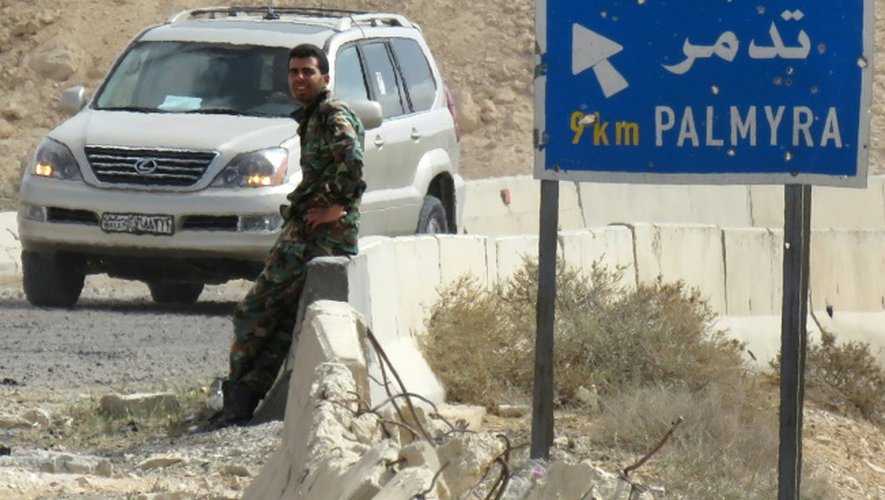 Un membre des forces gouvernementales syriennes près d'un panneau routier, le 27 mars 2016 à Palmyre