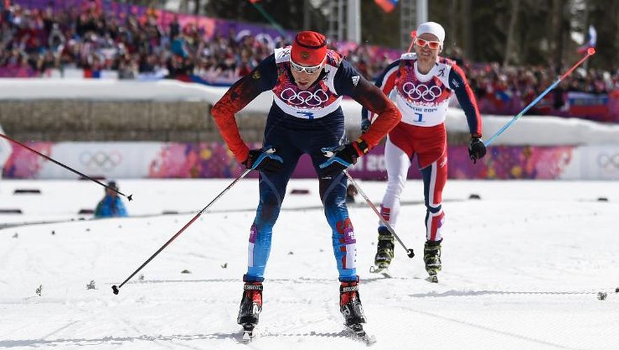 Le Russe Alexander Legkov (c) passe la ligne d'arrivée du 50 km de ski de fond et remporte la médaille d'or, le 23 février 2014 à Sotchi