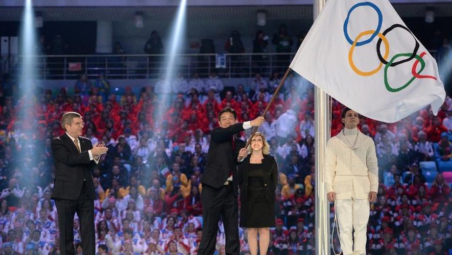 Thomas Bach, le président du Comité international olympique (g), applaudit après avoir donné le drapeau olympique au maire de PyeongChang (c), le 23 février 2014 lors de la cérémonie de clôture des Jeux de Sotchi