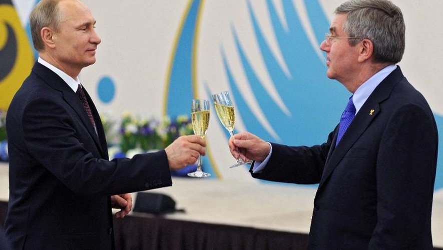 Vladimir Putin (G) avec le patron du CIO Thomas Bach (D) trinquent lors du déjeuner offert en l'honneur du comité d'organisation des Jeux de Sotchi, le 24 février 2014 sur le site