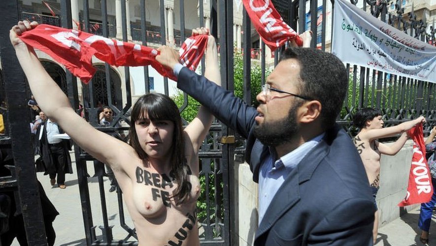 Un homme tente d'arracher un drapeau brandi par l'une des militantes Femen, le 29 mai 2013 à Tunis