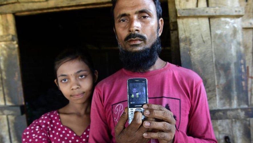 Abdur Rahman, sa fille à ses côtés, montre la photo de son fils Muhammad Shorif dans le camp Nayapara accueillant des Rohingyas à Teknaf, au Bangladesh le 15 mai 2015
