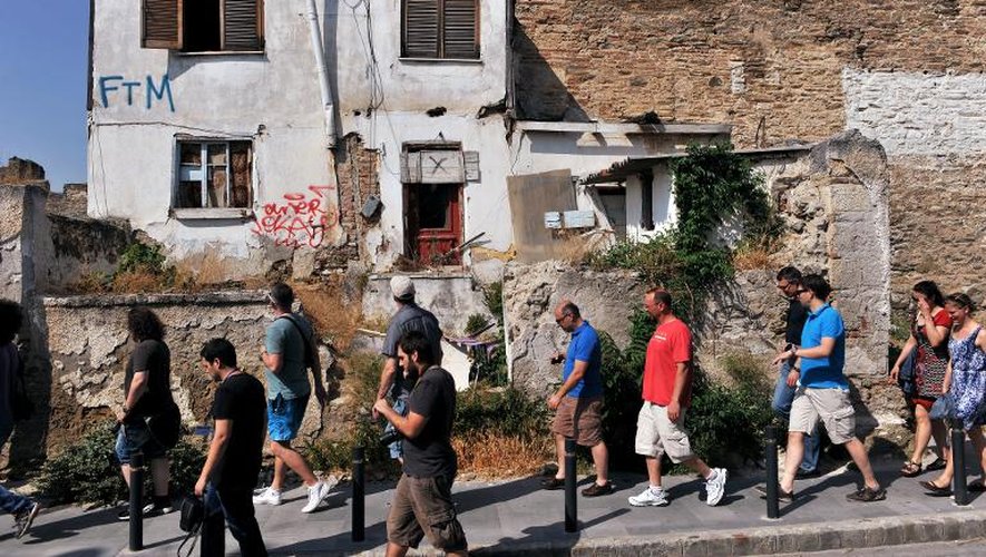 Des touristes passent devant une maison abandonnée au pied du château de Thessalonique, le 19 mai 2015