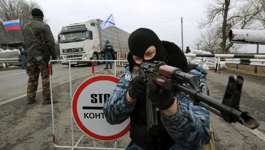 Un homme masqué pointe sa kalachnikov à un point de contrôle sur l'autoroute qui relie la Crimée à l'Ukraine le 28 février 2014 près de la ville de Armyansk
