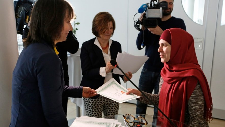 La journaliste et formatrice de l'ONG Femmes sans frontières (g) remet son diplôme à une élève tchéchène de l'"école des mères", à Vienne le 8 mars 2016