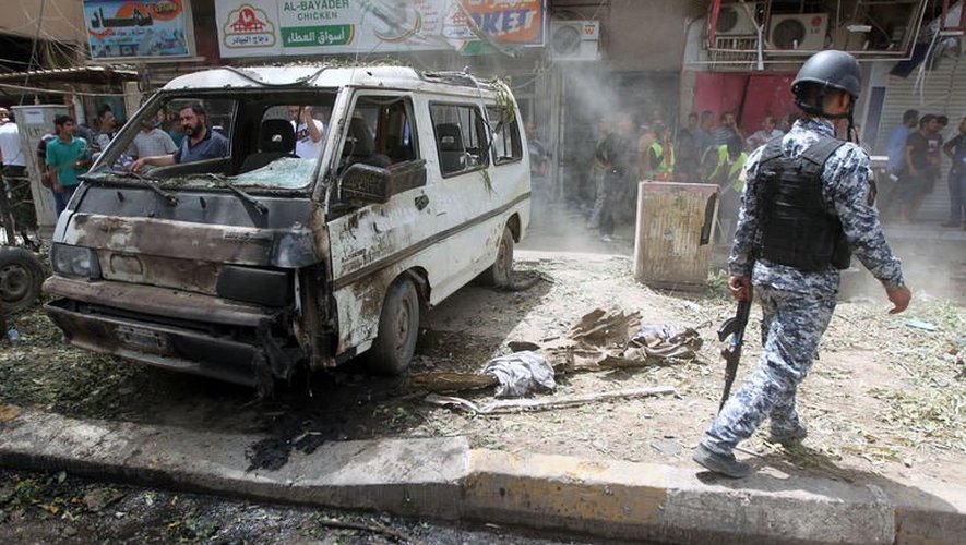 Un policier irakien inspecte les lieux de l'attentat à la voiture piégée qui a eu lieu le 30 mai 2013 à Bagdad
