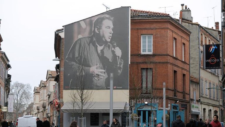 Des passants marchent devant un portrait du chanteur Claude Nougaro à Toulouse le 27 février 2014