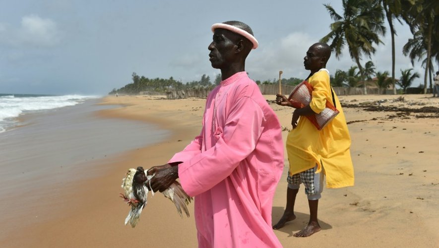 Un croyant tient deux pigeons et avance en direction de la mer, lors d'une prière sur la plage de Grand-Bassam en Côte d'Ivoire, le 1er avril 2016