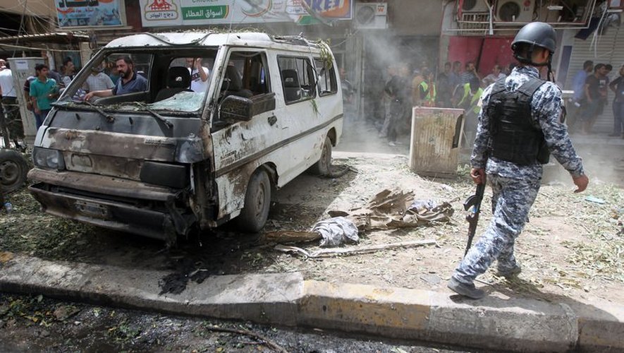 Un policier irakien près d'un véhicule calciné après un attentat à la voiture piégée, le 30 mai 2013 à Karradah près de Bagdad