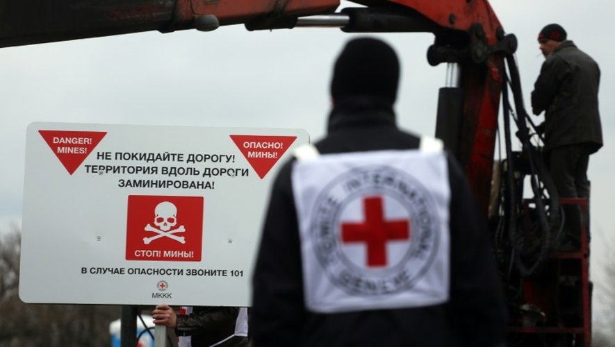 Des agents de la Croix-rouge installent des panneaux de prévention contre les mines "Danger de mines! Ne quittez pas la route!", sur le bord d'une route près du village de Berezové, dans la région de Donetsk, le 28 mars 2016