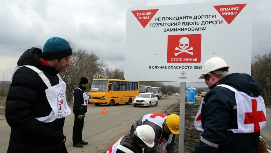 Des agents de la Croix-rouge installent des panneaux de prévention contre les mines "Danger de mines! Ne quittez pas la route!", sur le bord d'une route près du village de Berezové, dans la région de Donetsk, le 28 mars 2016