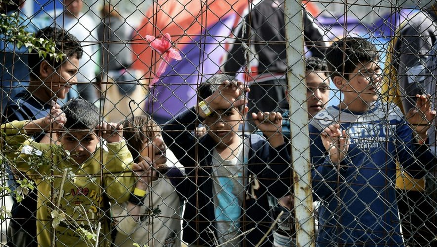 Des enfants se tiennent derrière le grillage entourant le camp de migrants de Moria transformé en camp de détention, à Mytilène, sur l'île grecque de Lesbos, le 3 avril 2016