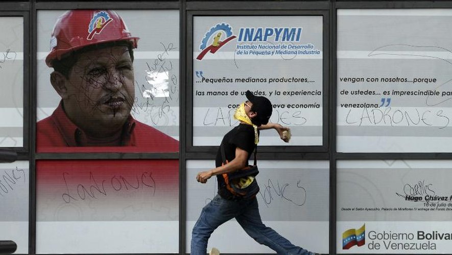 Un manifestant hostile au gouvernement de Nicolas Maduro devant une représentation de l'ancien président du Venezuela Hugo Chavez, le 22 février 2014 à Caracas