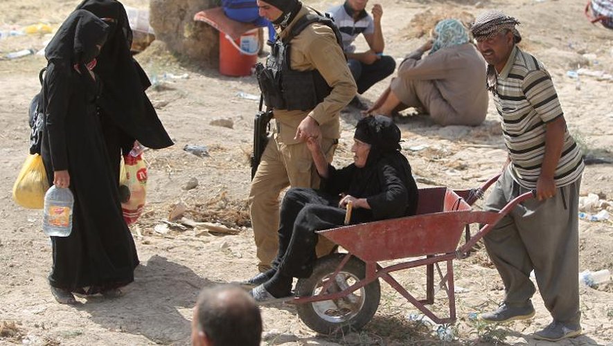 Un homme armé accompagne une femme irakienne âgée ayant échappé de l'avancée des jihadistes de l'EI à Ramadi, le 22 mai 2015 près du pont Bzeibez, sur le chemin de Bagdad
