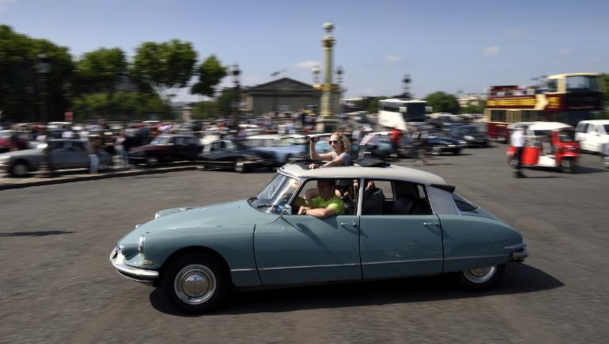 Une Citroën DS circule Place de la Concorde à Paris le 24 mai 2015 pour célébrer les 60 ans de cette automobile emblématique de la France conquérante des Trente glorieuses