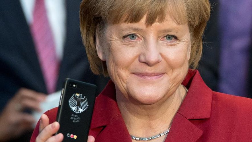 La chancelière allemande Angela Merkel tenant un téléphone portable crypté à l'ouverture  du Cebit de Hanovre, le 5 mars 2013