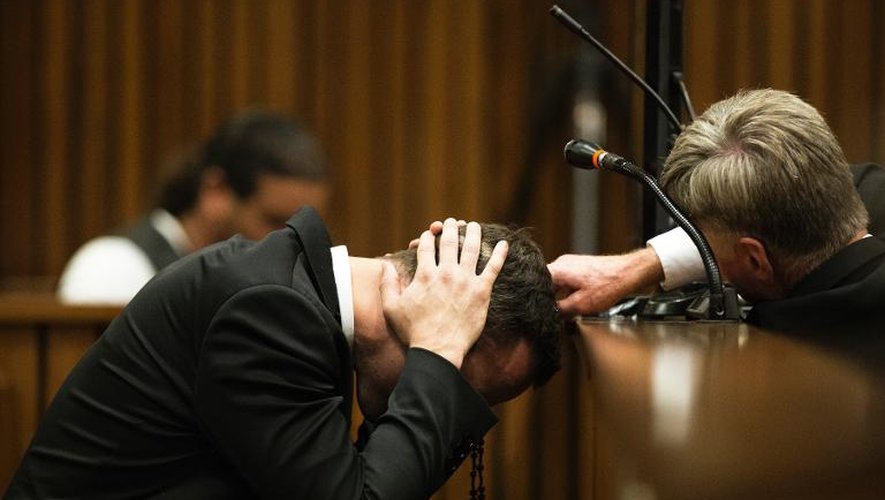Oscar Pistorius, affaissé dans son box et couvrant ses oreilles de ses mains, le 6 mars 23014 au tribunal à Pretoria