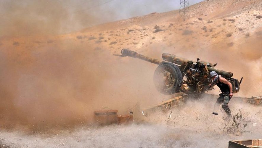 Un soldat syrien ouvre le feu le 17 mai 2015 avec une pièce d'artillerie sur des positions des islamistes du groupe EI au nord-est de Palmyre