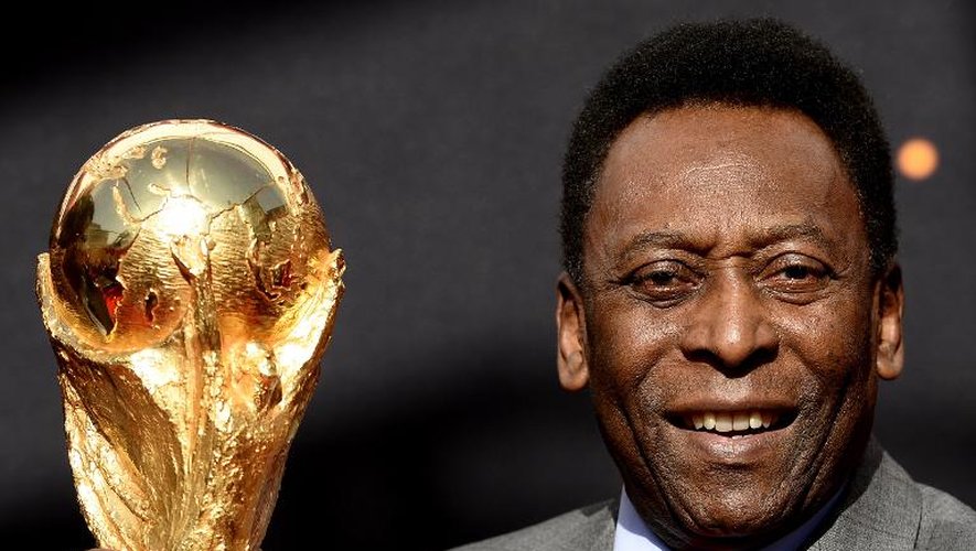 La légende du football le "Roi" Pelé pose avec la Coupe du monde de football lors d'une conférence de presse le 9 mars 2014 devant l'Hôtel de ville de Paris