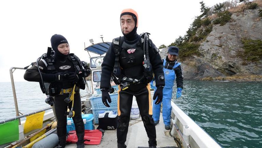 Yasuo Takamatsu (C) s'apprête à plonger à Onagawa, sur la côte est du Japon, pour tenter de retrouver sa femme disparue dans le tsunami, le 2 mars 2014