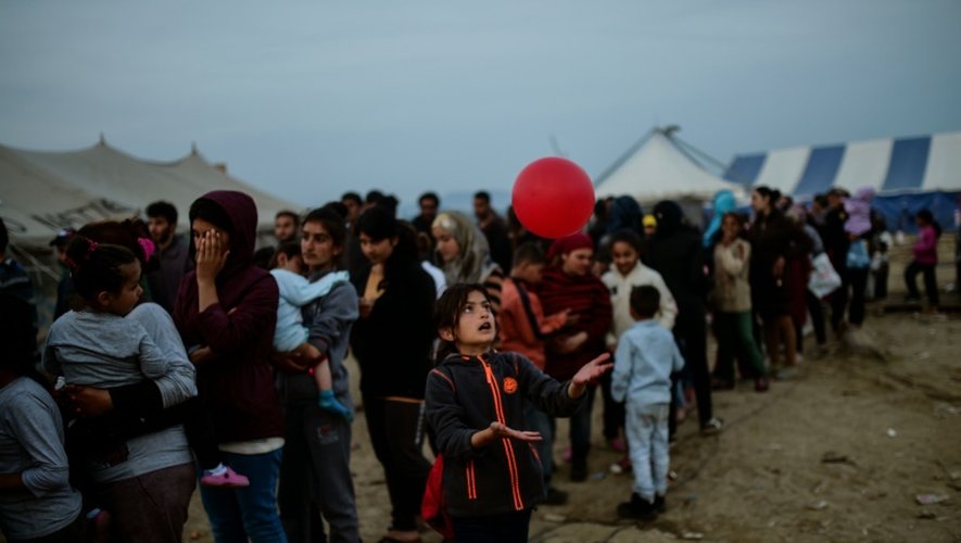 Une jeune migrante joue avec un ballon en attendant une distribution de nourriture dans le camp de migrants à la frontière gréco-macédonienne d'Idomeni, le 5 avril 2016