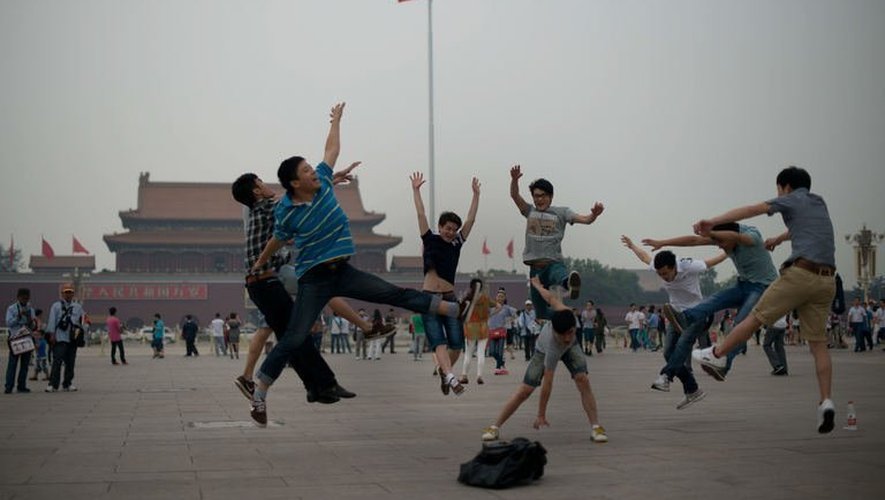 Des touristes sautent en l'air pendant que leurs amis les prennent en photo sur la place Tiananmen à Pékin, le 4 juin 2013
