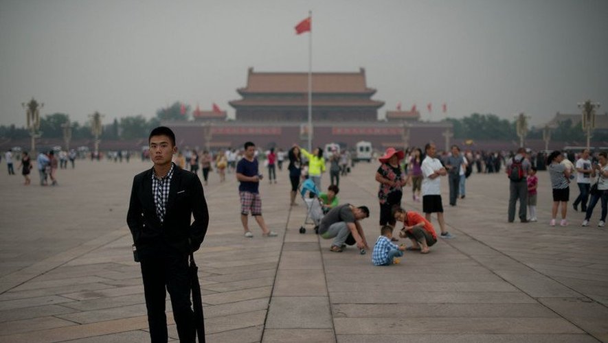 Un policier en civil (G) suit des journalistes sur la place Tiananmen à Pékin le 4 juin 2013