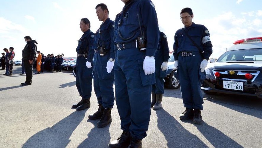 Des policiers japonais observent une minute de silence en hommage aux victimes du tsunami de 2011, à Namie le 11 mars 2014