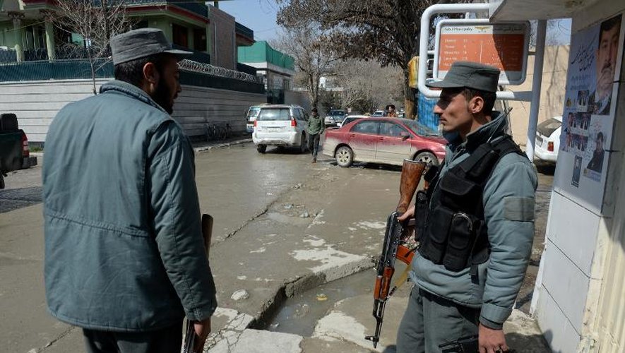 Deux policiers afghans se tiennent sur le lieu de l'assassinat d'un journaliste anglo-suédois à Kaboul le 11 mars 2014