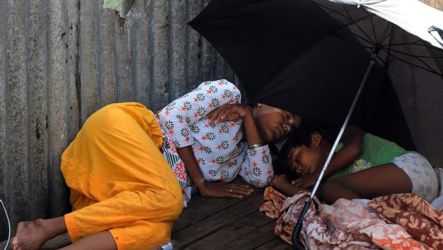 Une femme et un enfant dorment sous une ombrelle au bord de la rue à Calcutta, le 27 mai 2015