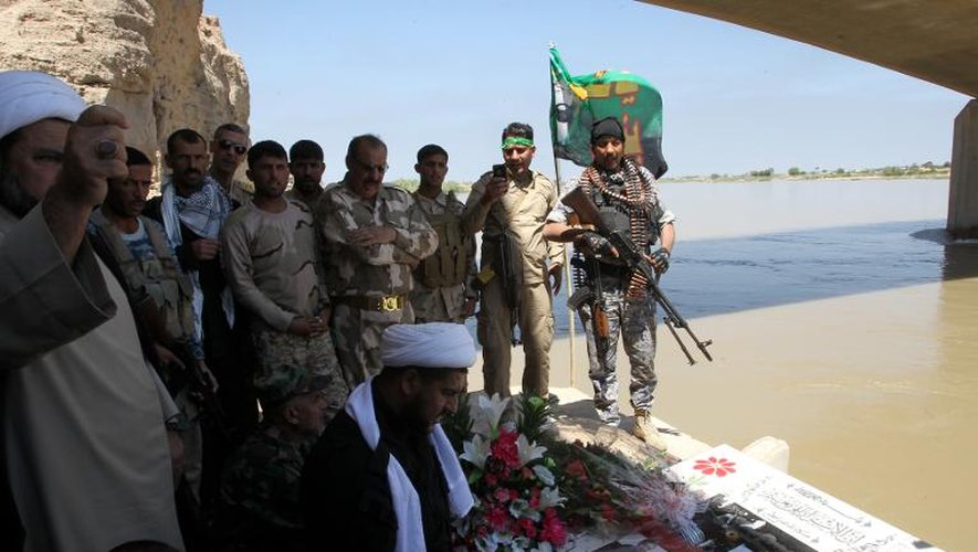 Des membres des forces de sécurité irakiennes prient lors d'une cérémonie en hommage aux personnes massacrées par le groupe Etat islamique à Tikrit, le 15 avril 2015