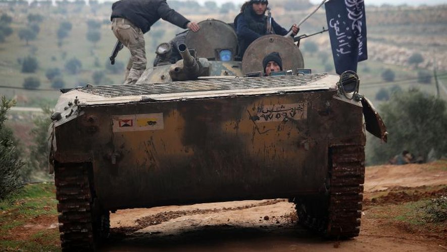 Des combattants du Front Al-Nosra sur un char pris aux forces gouvernementales le 19 décembre 2014 au sud d'Alep, dans le nord de la Syrie