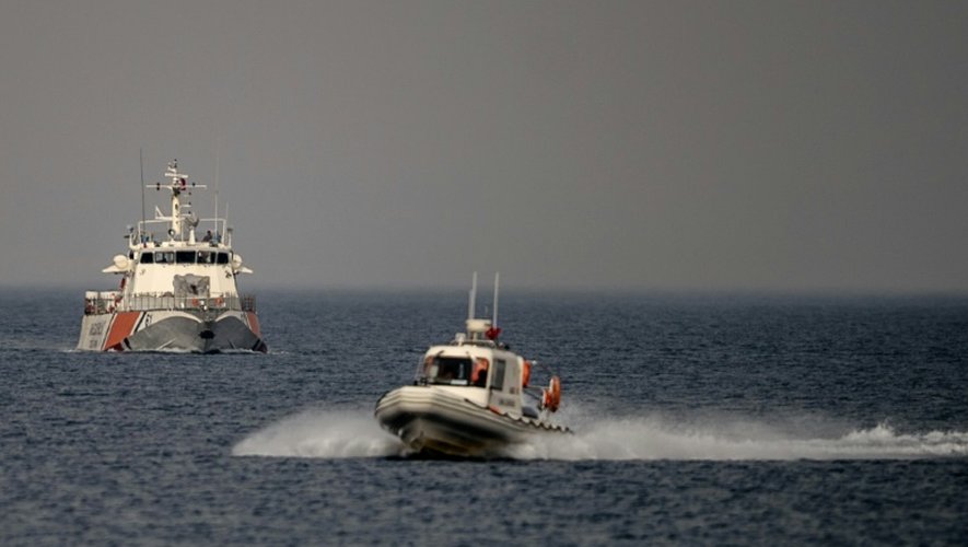 Un navire des gardes-côtes (d) escorte le ferry transportant le deuxième groupe de migrants renvoyés depuis les îles grecques vers la Turquie, le 8 avril 2016 à leur arrivée au port turc de Dikili